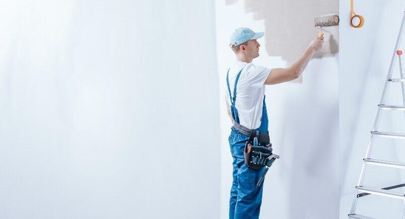 A painting company employee painting a wall